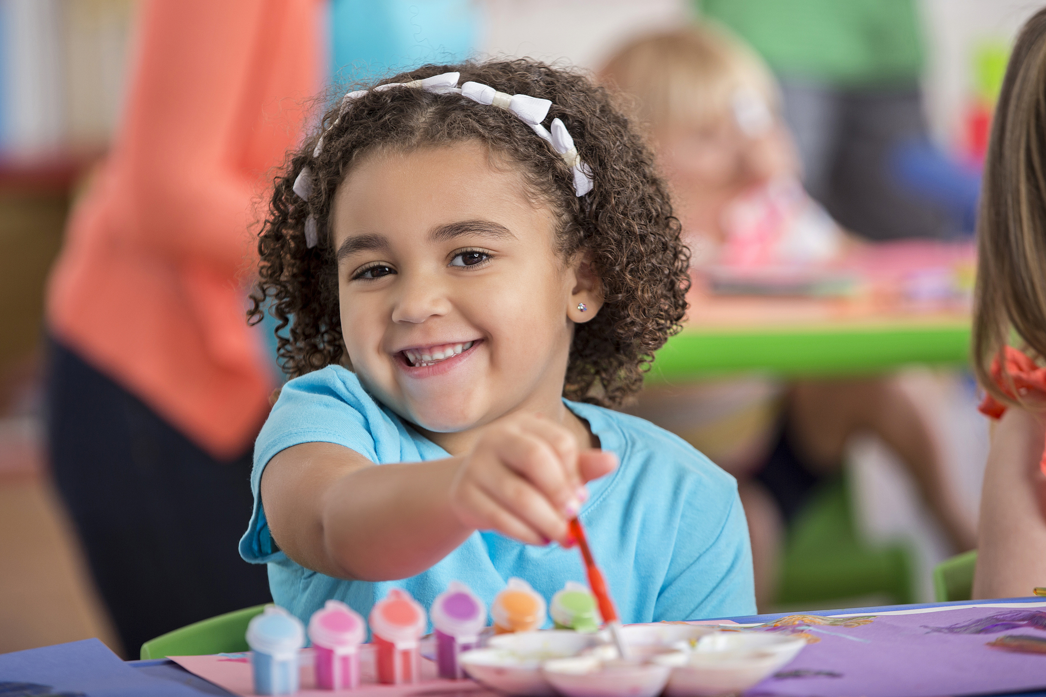 A child smiling with paint-covered hands
