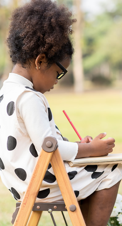 A girl drawing at a desk outdoors