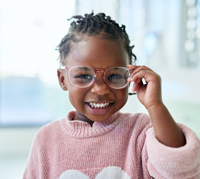 A smiling preschooler trying on eyeglasses