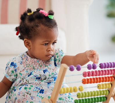 A toddler counting on a colorful abacus